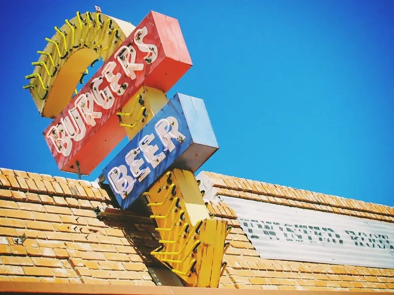 Meilleur burger à Dallas : enseigne néon vintage Burgers et Beer sur un toit en brique de Deep Ellum, sous le ciel bleu du Texas