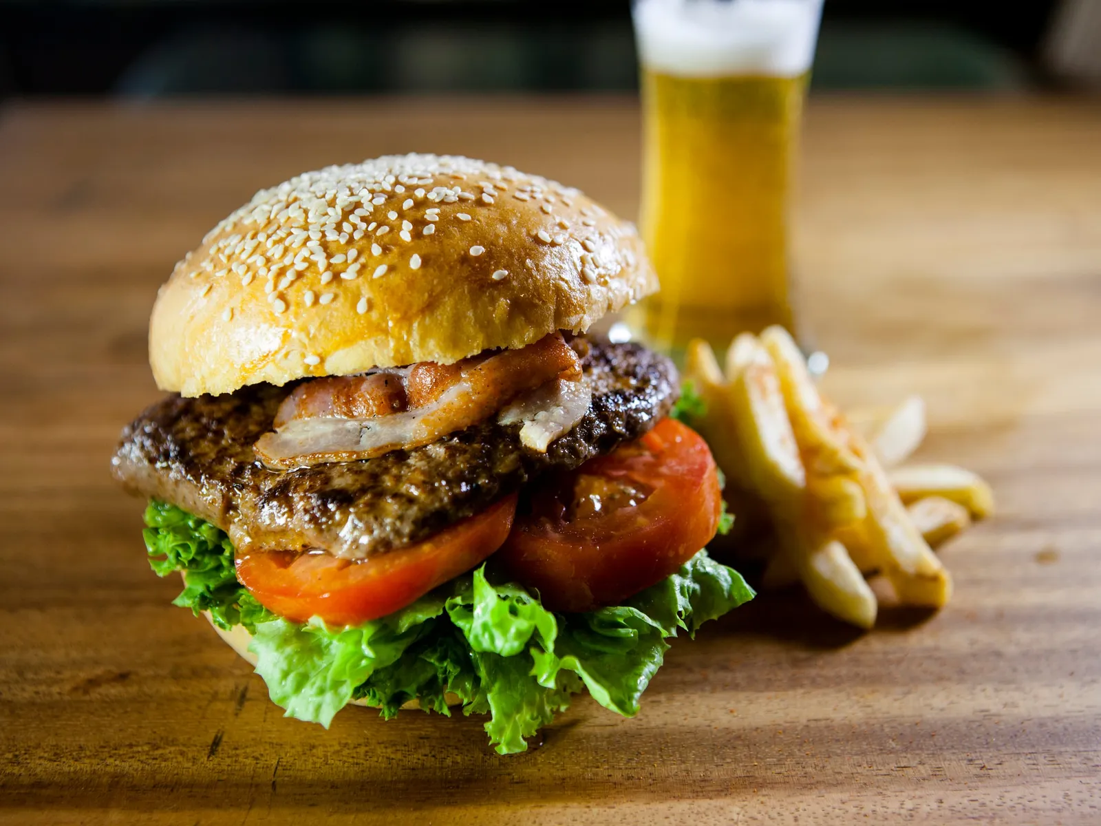 Hamburguesa de ternera a la parrilla con beicon, tomate y lechuga en pan de sésamo, el estilo de las mejores hamburguesas de Hamburgo