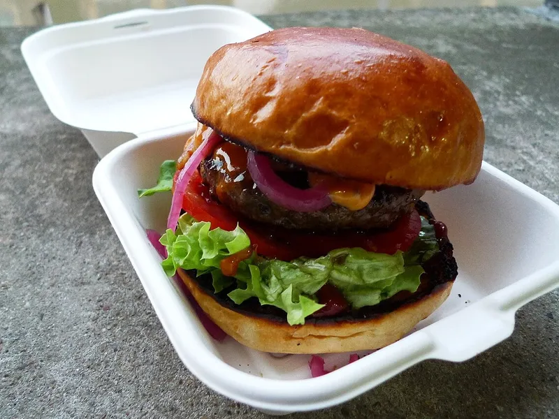 Meilleurs burgers à Londres : burger au bœuf Patty&Bun, oignon rouge et salade dans un bun brioché, servi en boîte à emporter