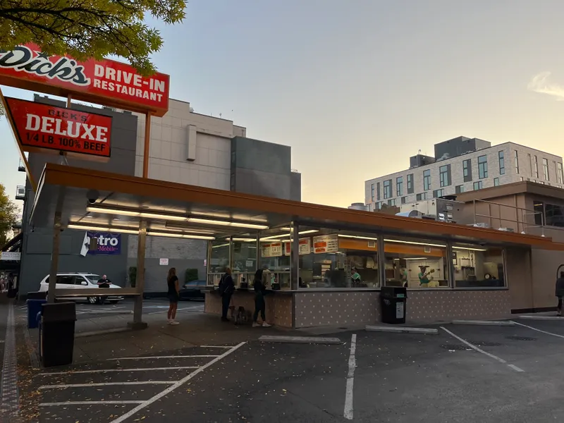 Best burgers in Seattle: the Dick's Drive-In walk-up counter on Broadway, Capitol Hill, under its red Dick's Deluxe sign at dusk