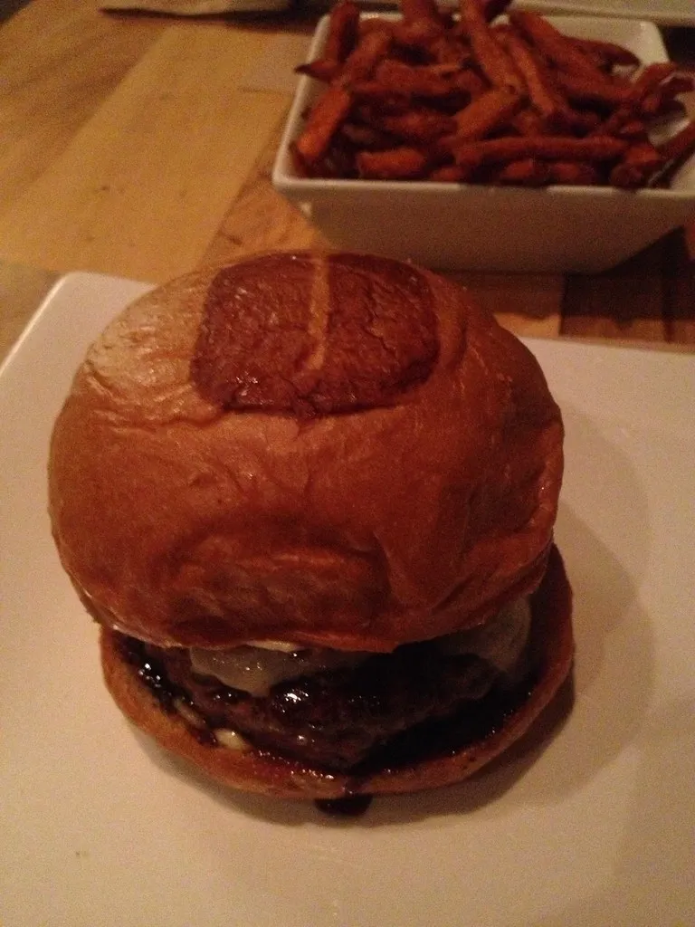 Truffle burger with melted cheese on a glossy bun and sweet potato fries, illustrating Shake Shack’s Black Truffle return