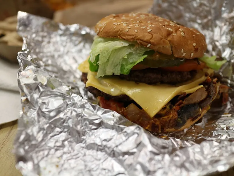 Cheeseburger Five Guys à deux steaks de bœuf, fromage fondu et garnitures sur pain sésame toasté