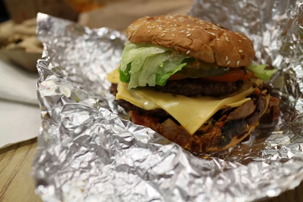 Five Guys cheeseburger with two beef patties, melted cheese and toppings on a toasted sesame bun