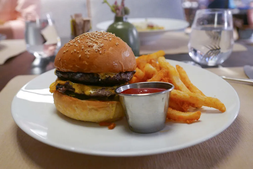 Double cheeseburger with melted cheddar and pickles on a sesame bun with fries