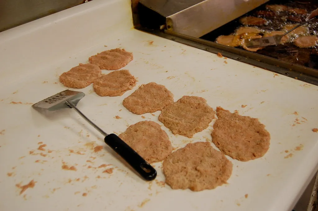Thin, wide raw beef patties shaped for a copycat Whopper before grilling