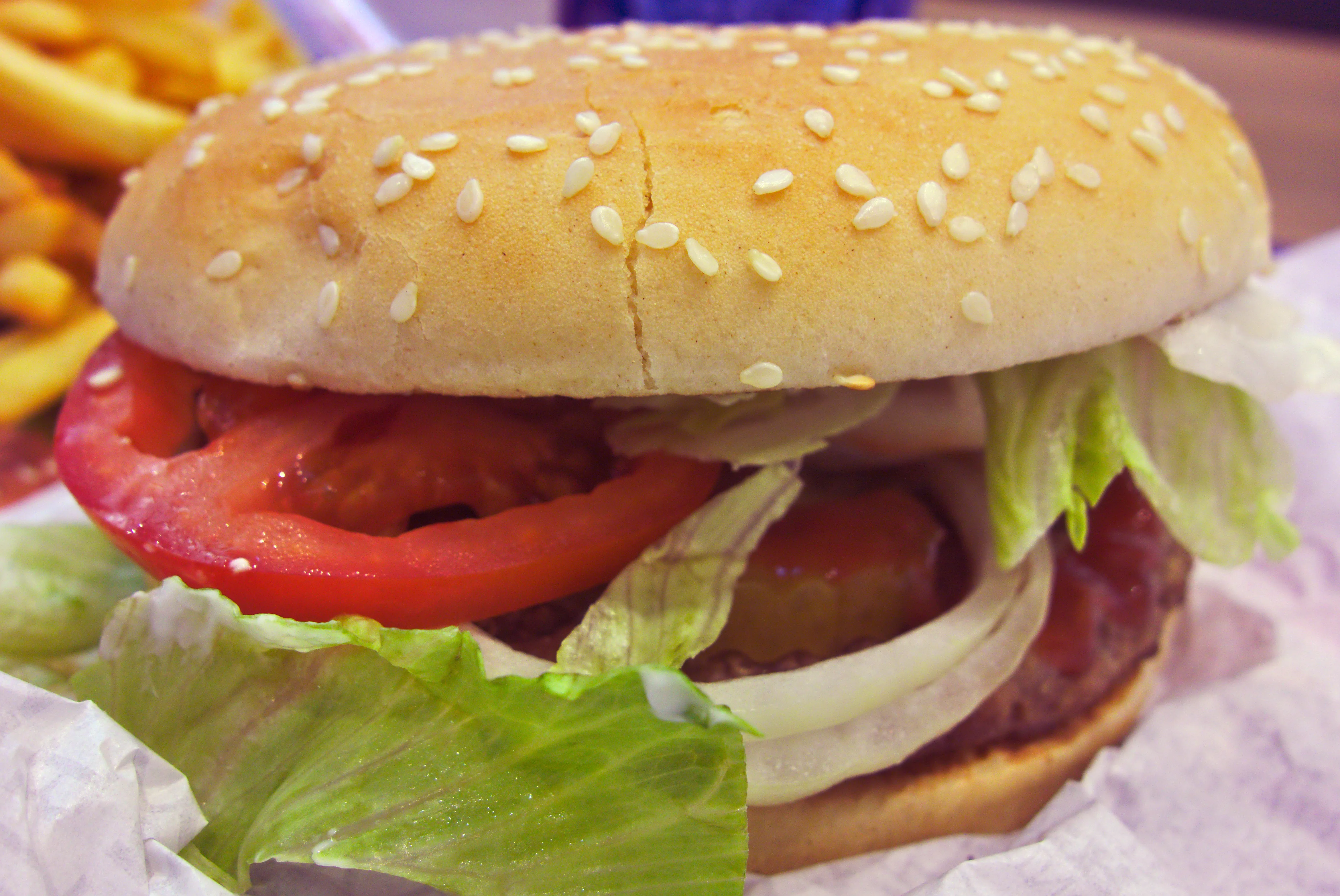 Classic single Burger King Whopper with one flame-grilled patty, tomato, lettuce and onion on a sesame bun