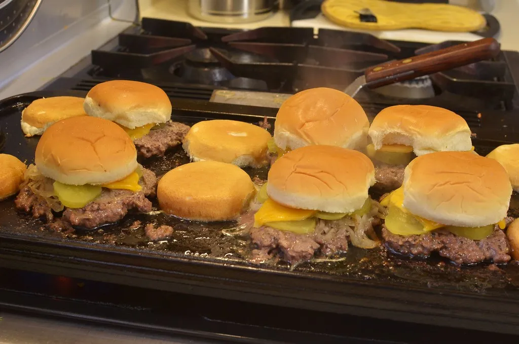 Smashing patty for ShackBurger recipe copycat — small patties searing on a hot griddle with cheese melting