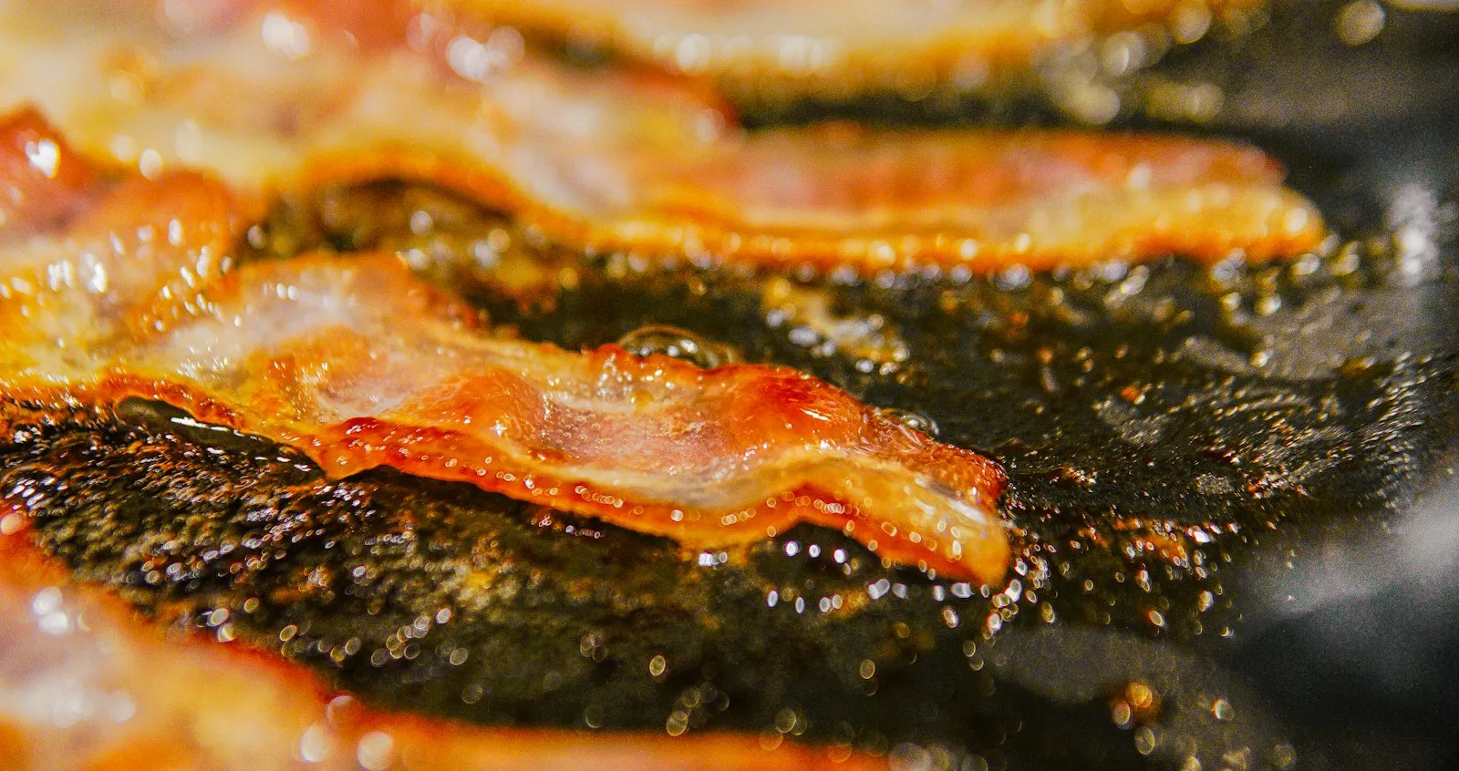 Thick-cut smoked bacon strips rendering until crisp for a homemade Bacon King