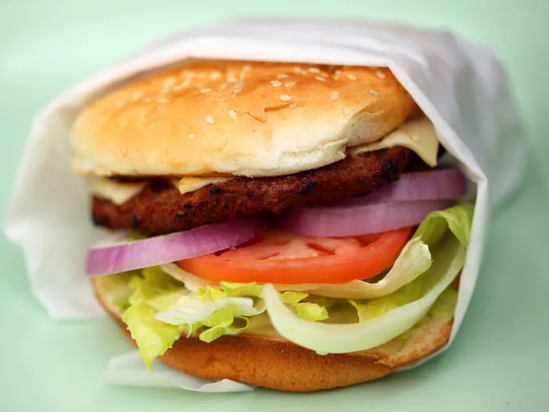 Cheeseburger with a grilled beef patty, melted American cheese, lettuce, tomato and onion on a bun, the toppings of a Carl's Jr. Famous Star copycat