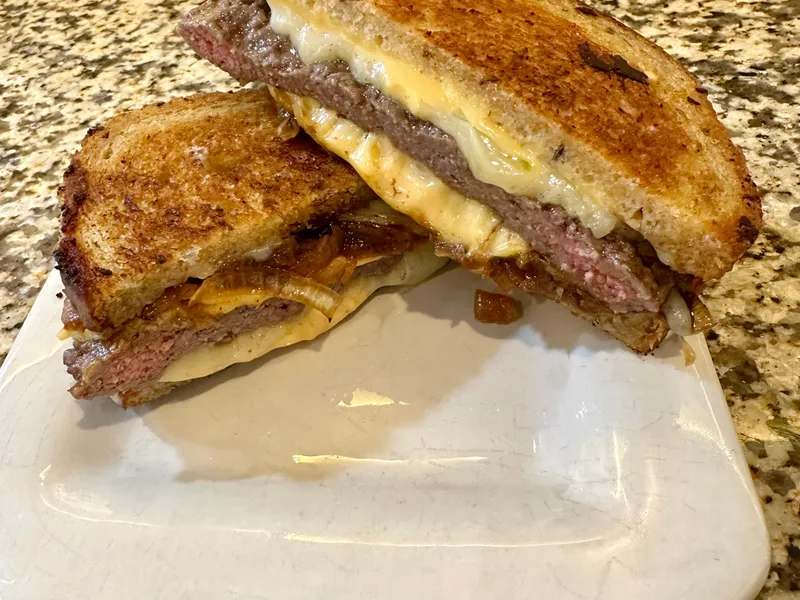 Recette patty melt maison façon Sourdough Melt de Culver's : sandwich coupé en deux, fromage fondu et steak saisi entre deux tranches de pain toasté