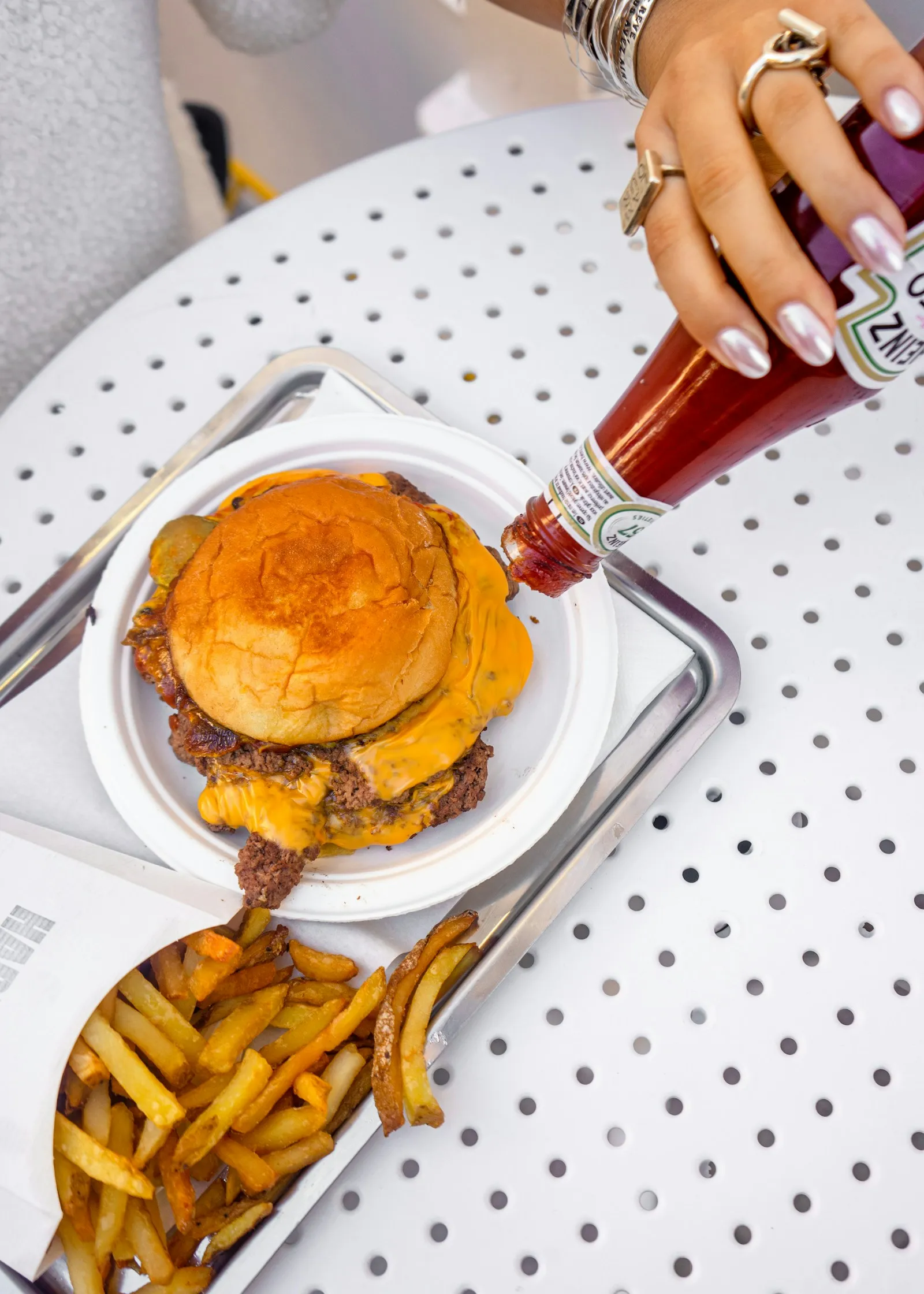 Ketchup being added to a double cheeseburger with molten American cheese