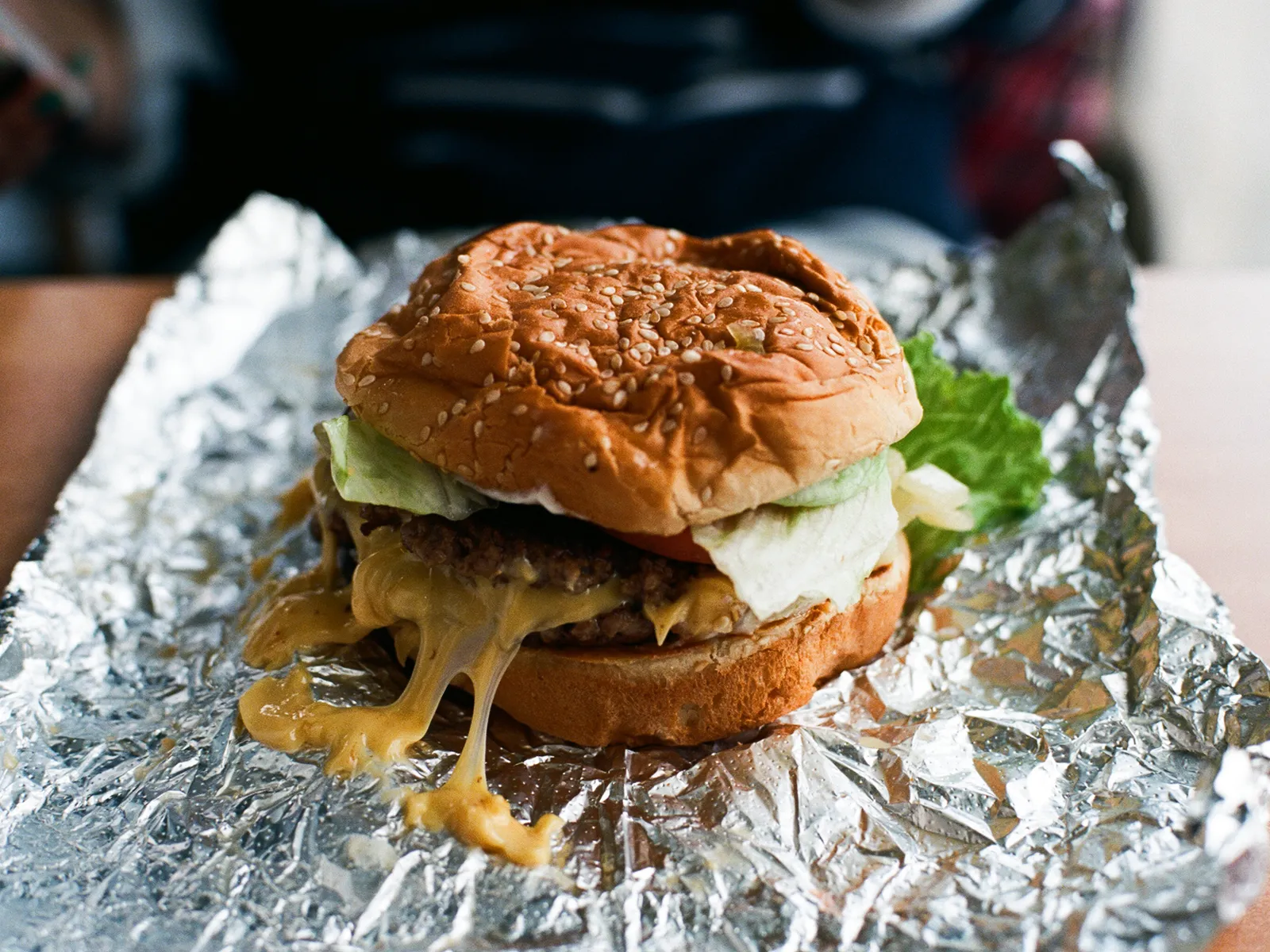 Burger double Five Guys ouvert sur sa feuille d'aluminium : deux steaks fins, laitue et tomate dans un pain au sésame toasté, l'emballage alu repris dans la recette du Bacon Burger maison