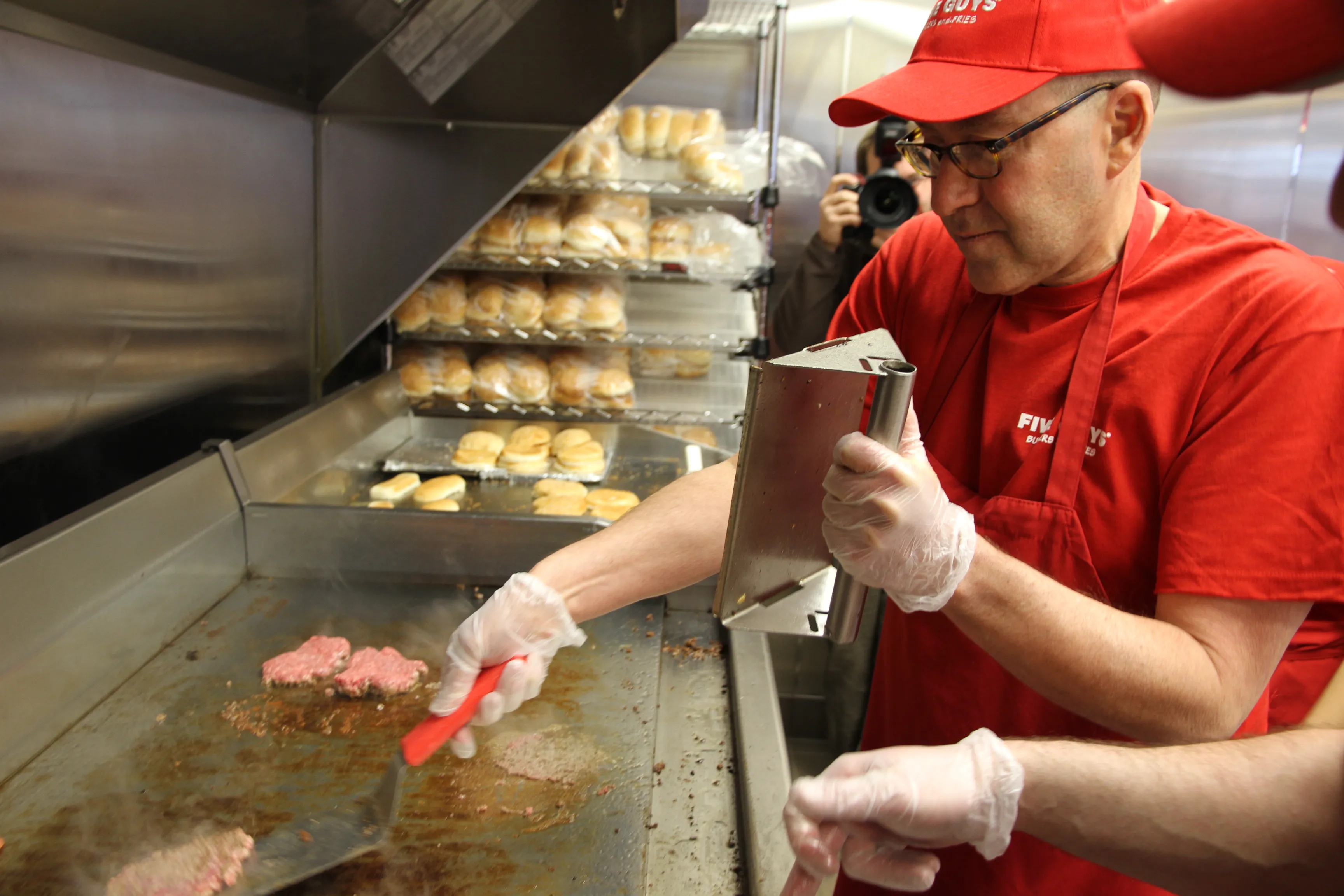 Filetes de hamburguesa en la plancha de una cocina Five Guys, cocinados bien hechos