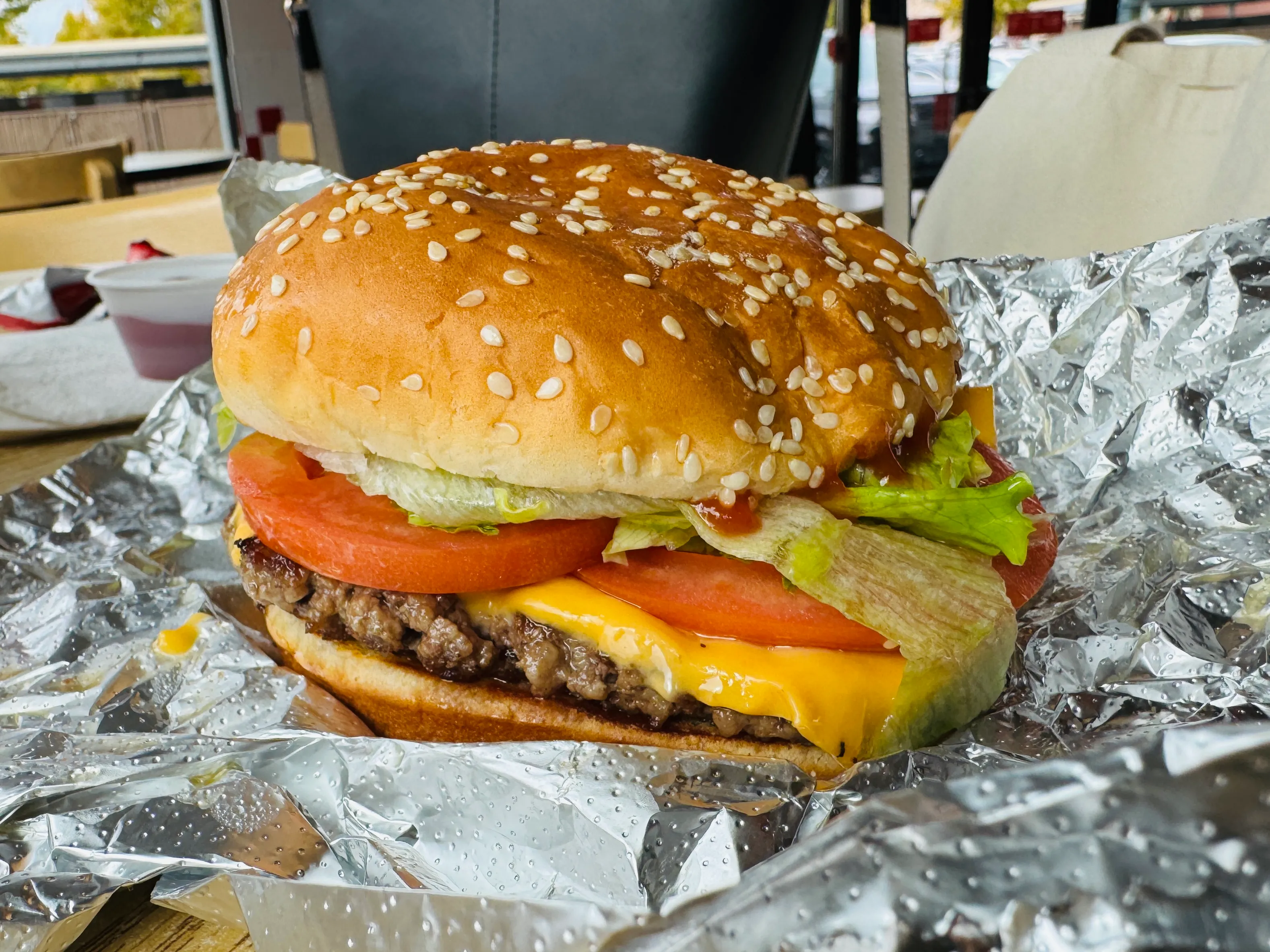 Five Guys Little Cheeseburger with one patty, lettuce, tomato and ketchup on a sesame bun