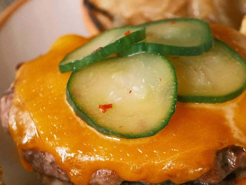 Hardee's Big Cheeseburger copycat at home: a grilled beef patty under melted cheese and dill pickles on a toasted bun