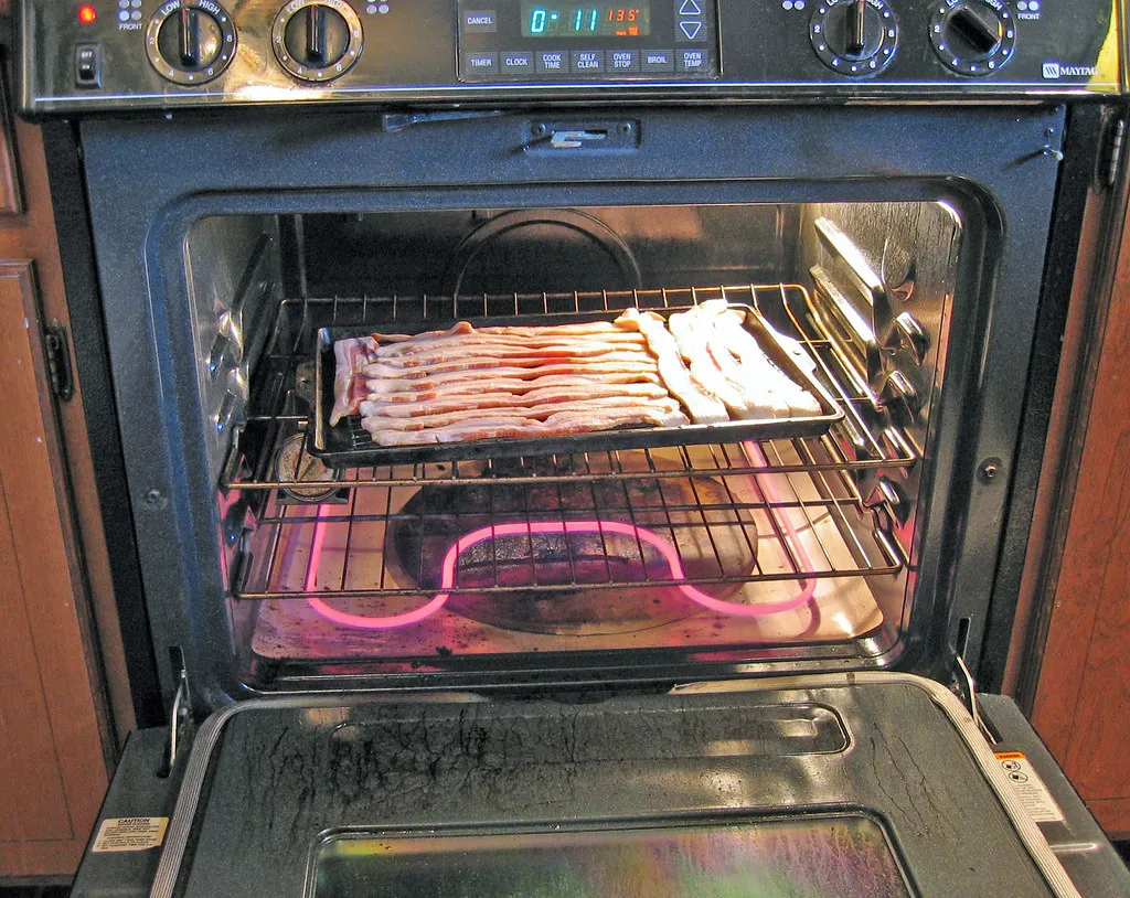 Bacon strips laid flat on a sheet pan before baking, the oven method for a Monster Thickburger copycat