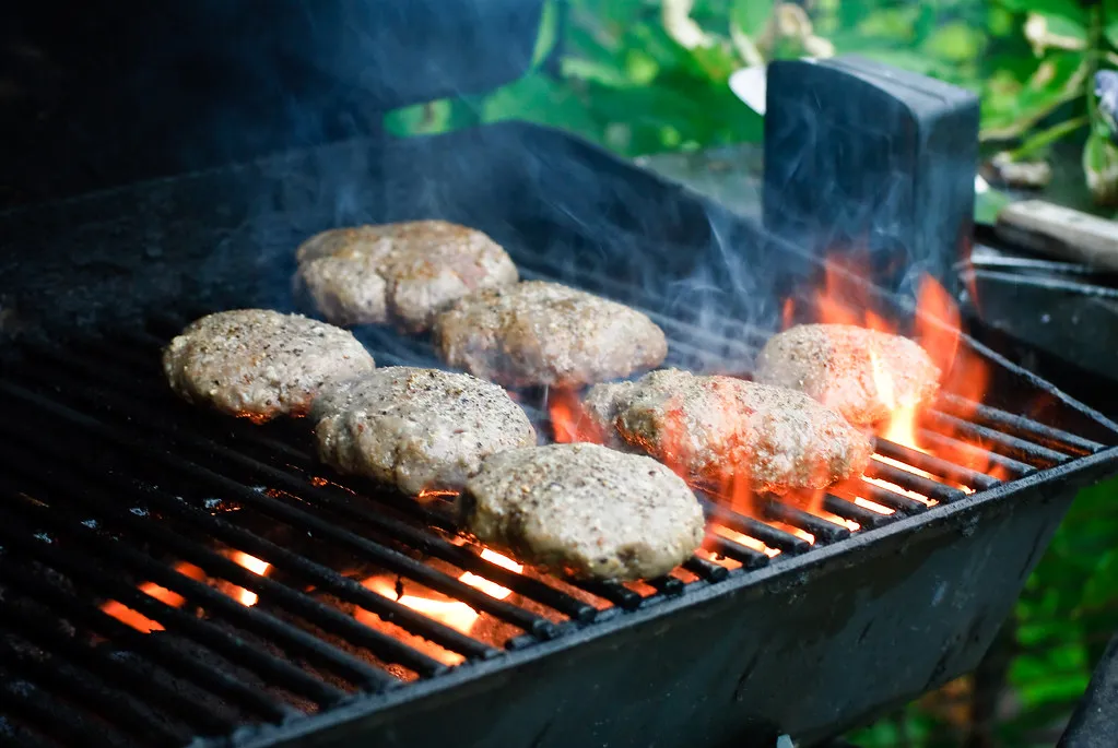 Burger patties flame-grilling over an open fire for a homemade Double Big Jack