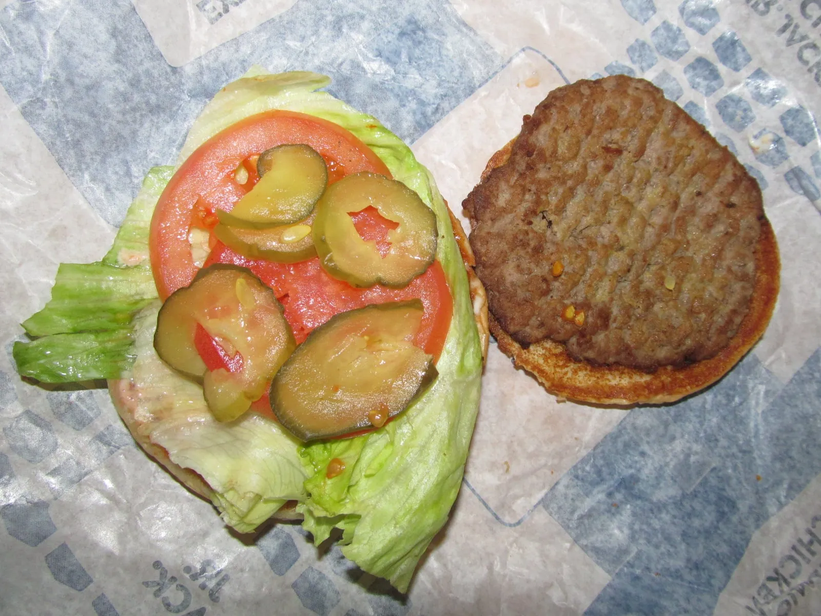 Intérieur d’un Jr. Jumbo Jack de Jack in the Box : steak de bœuf fin sous la tomate, la laitue et les cornichons à l’aneth
