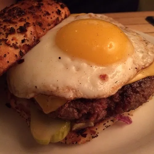 Beef burger topped with melted cheese and a fried egg with runny yolk