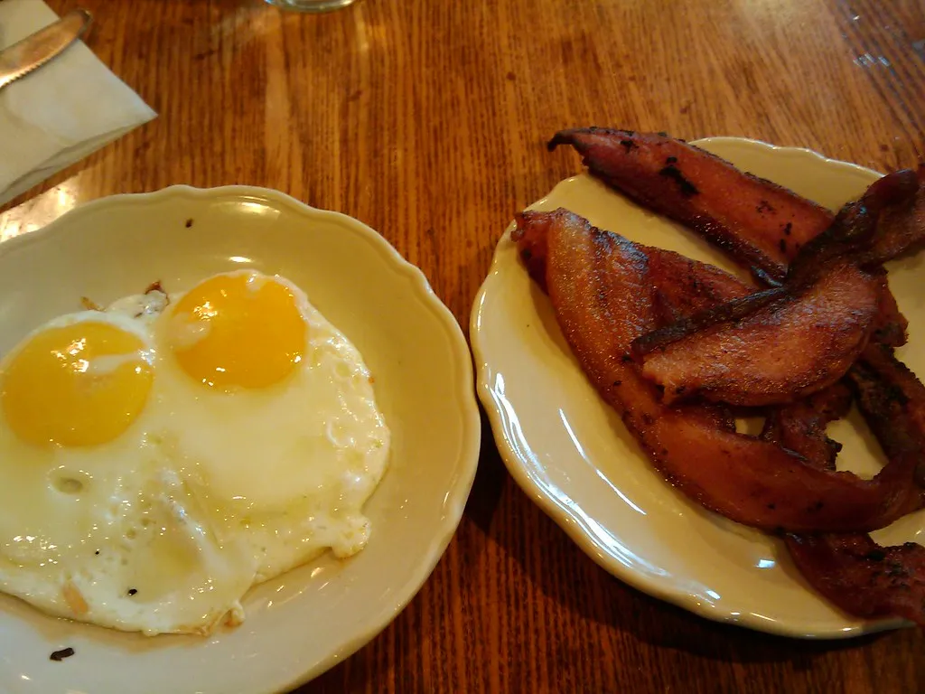 Sunny-side-up fried eggs with fully runny yolks cooking in a pan
