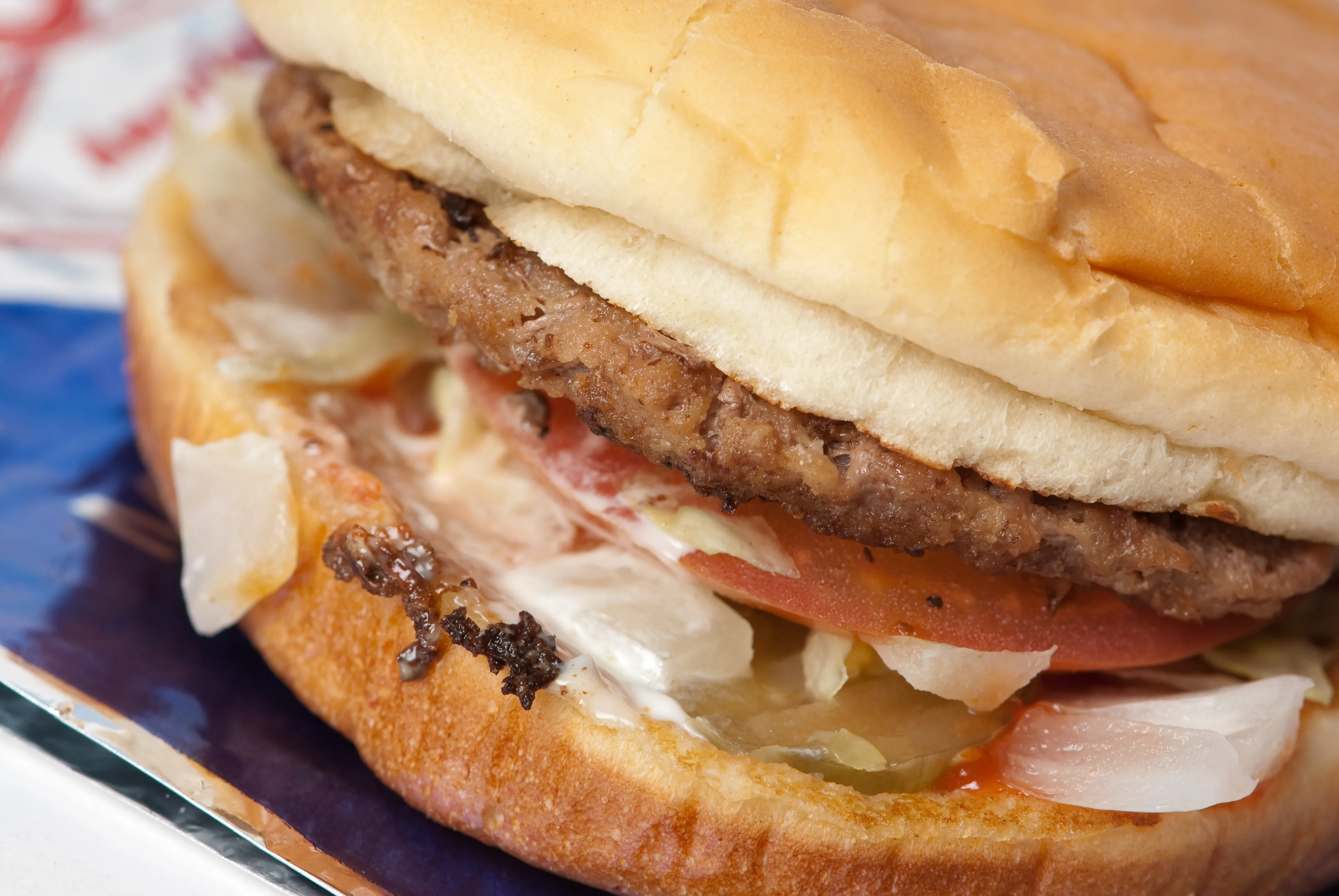 Sonic Jr. Deluxe burger with a thin junior patty on a toasted soft white bun, the same bun and patty format as the Jr. Double Cheeseburger