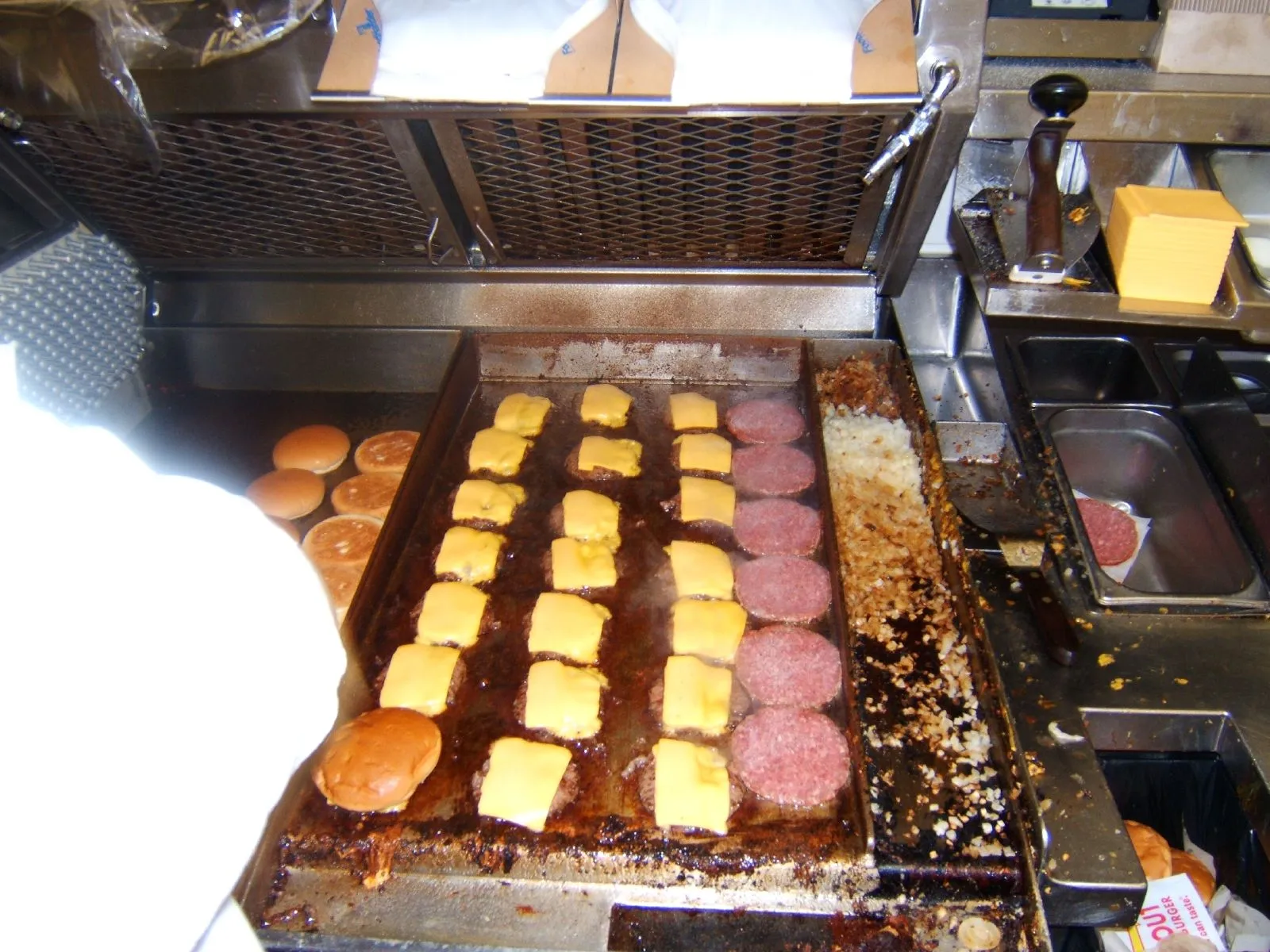 American cheese slices melting on beef patties searing on a flat-top griddle