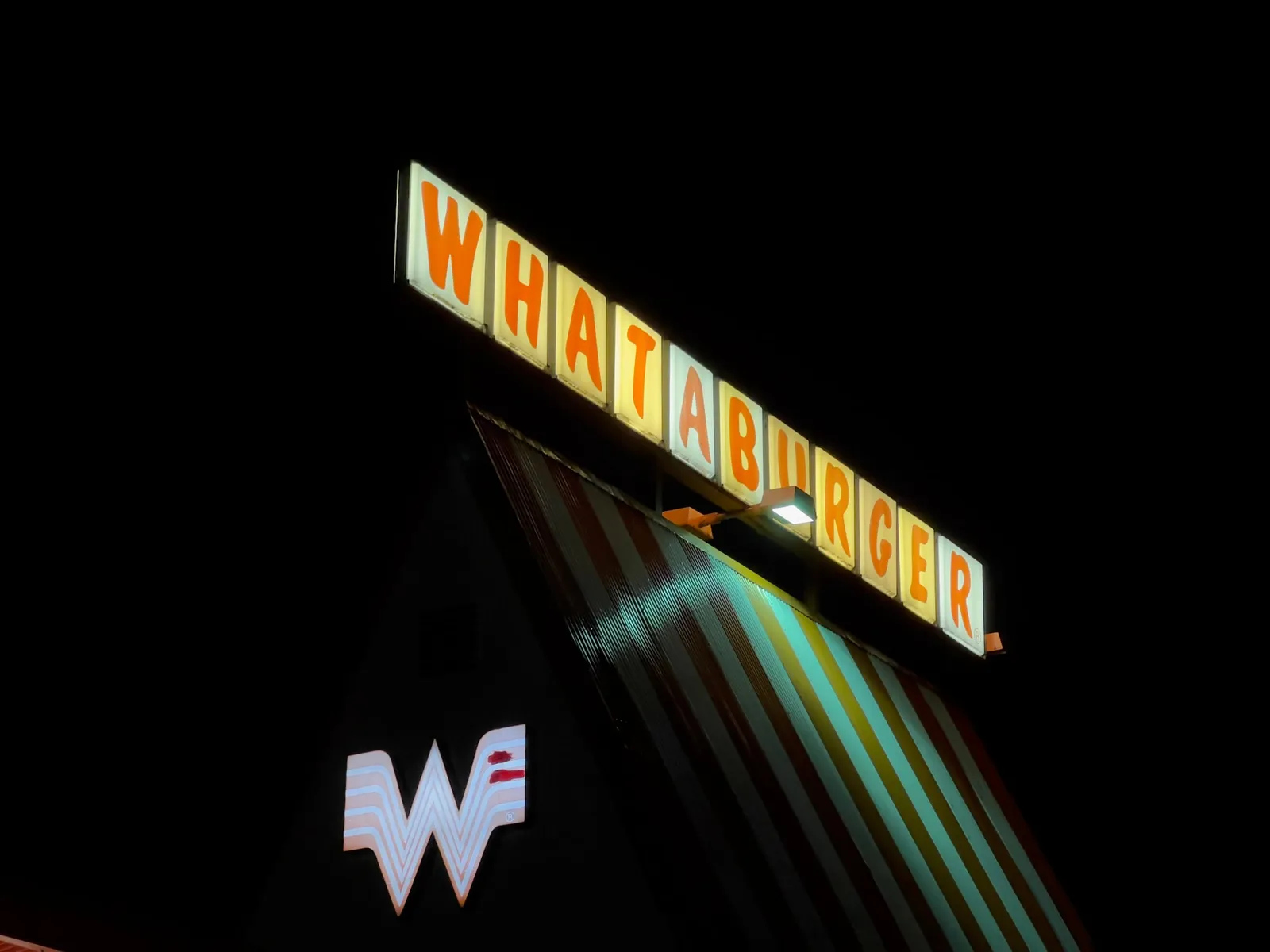 Whataburger Austin n° 84 sur Cameron Road la nuit : l'enseigne orange et blanche allumée au-dessus du toit rayé en A et du logo W