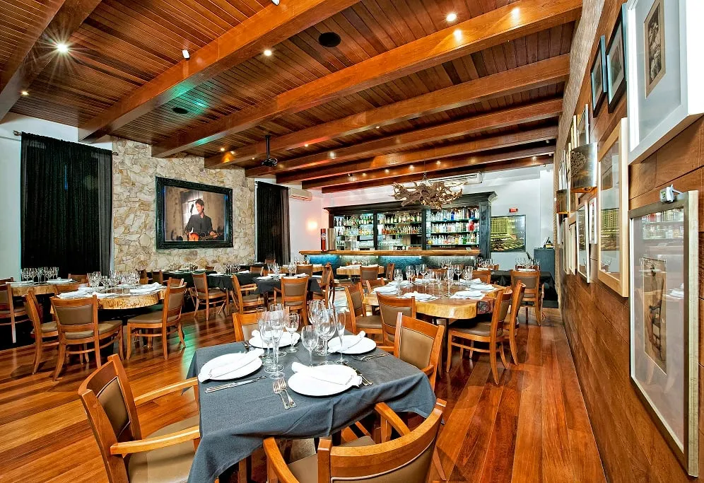 Salón del Madero Prime Steak House en Curitiba, con vigas de madera, paredes de piedra y barra