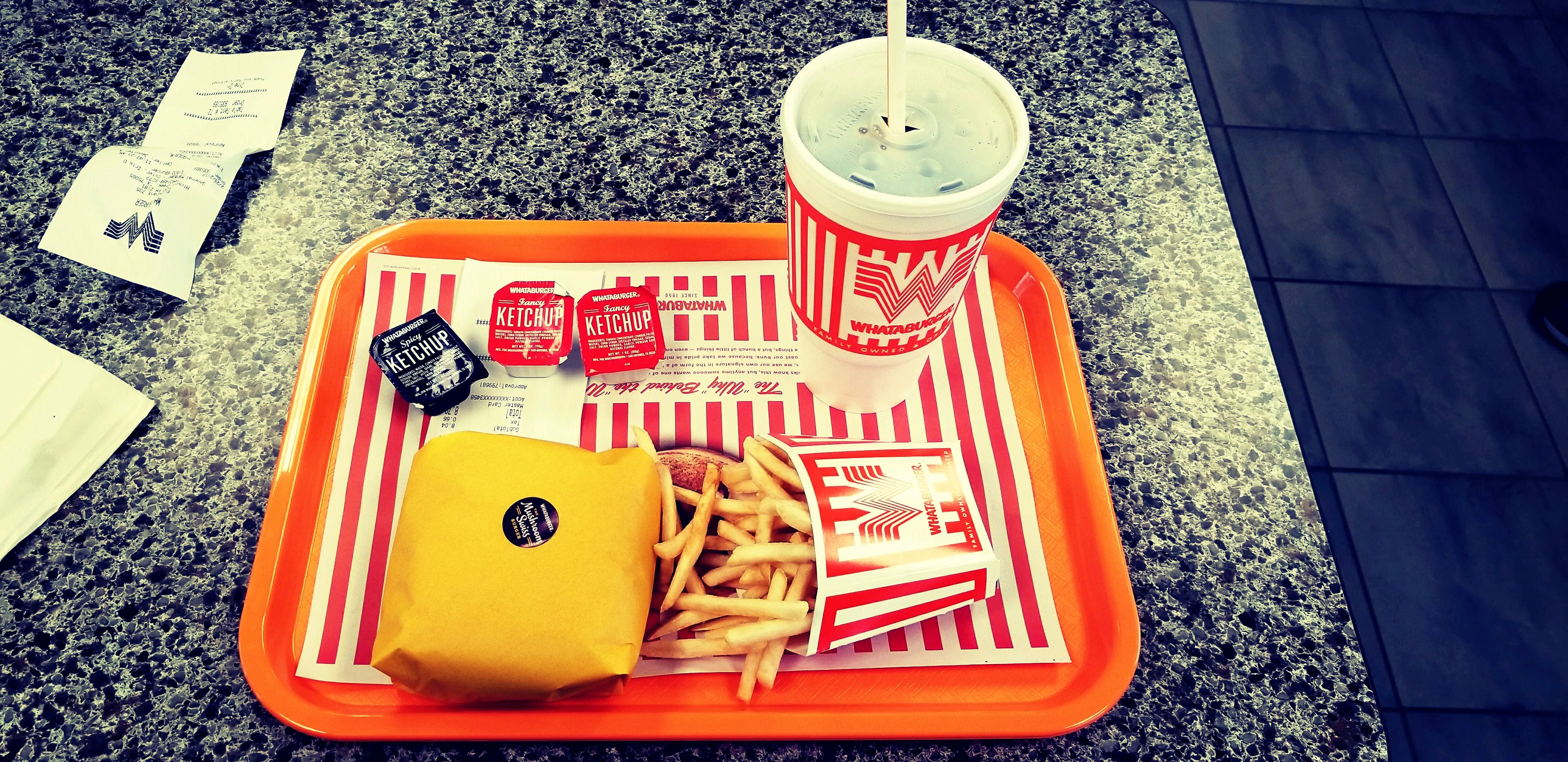 Whataburger order on an orange tray with burger, fries, Fancy Ketchup and Spicy Ketchup