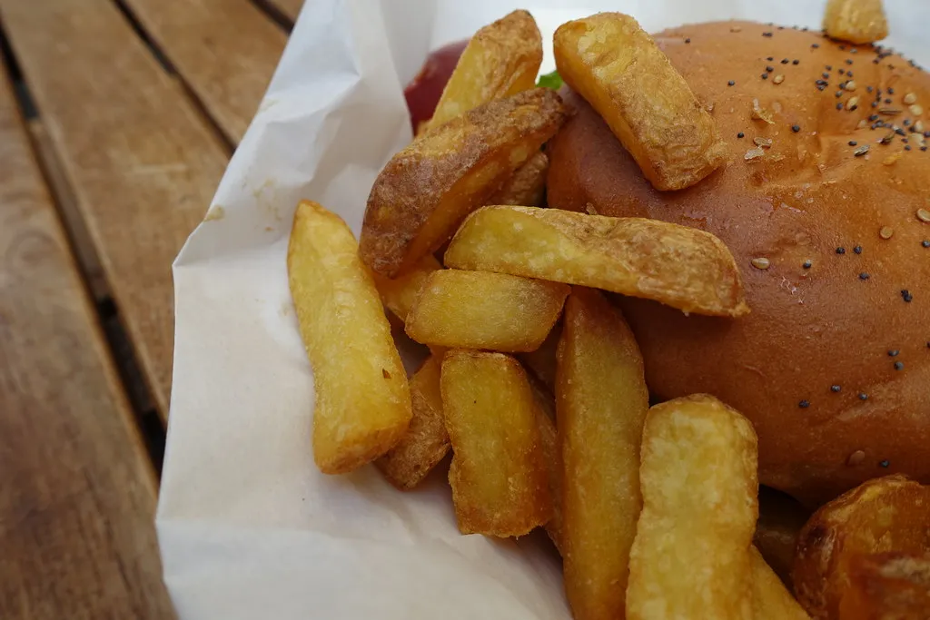 Patatas fritas gruesas y pan con sésamo y amapola de una hamburguesa de Holy Cow! en Lausana