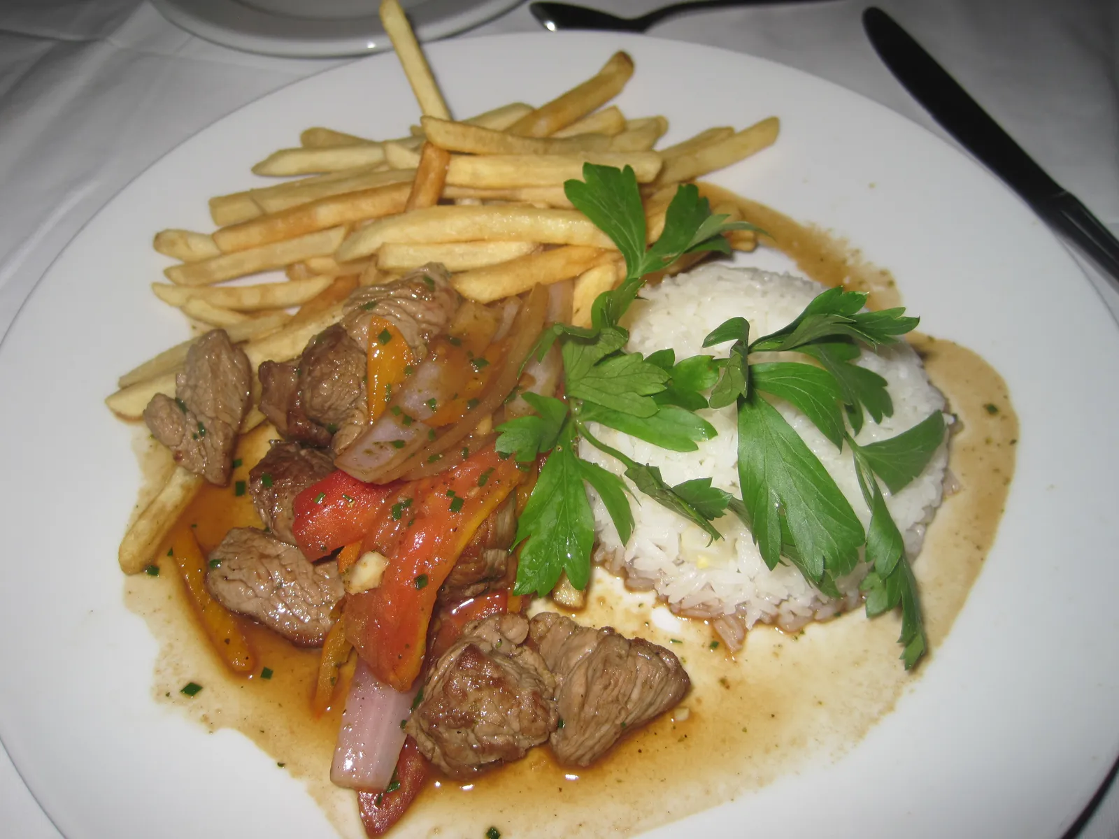 Lomo saltado, the Peruvian beef stir-fry with onion, tomato and fries behind the Lomo Saltado Smash at Renzo Garibaldi's Osso Burger in Lima (dish shown in Miraflores, not at Osso Lima)