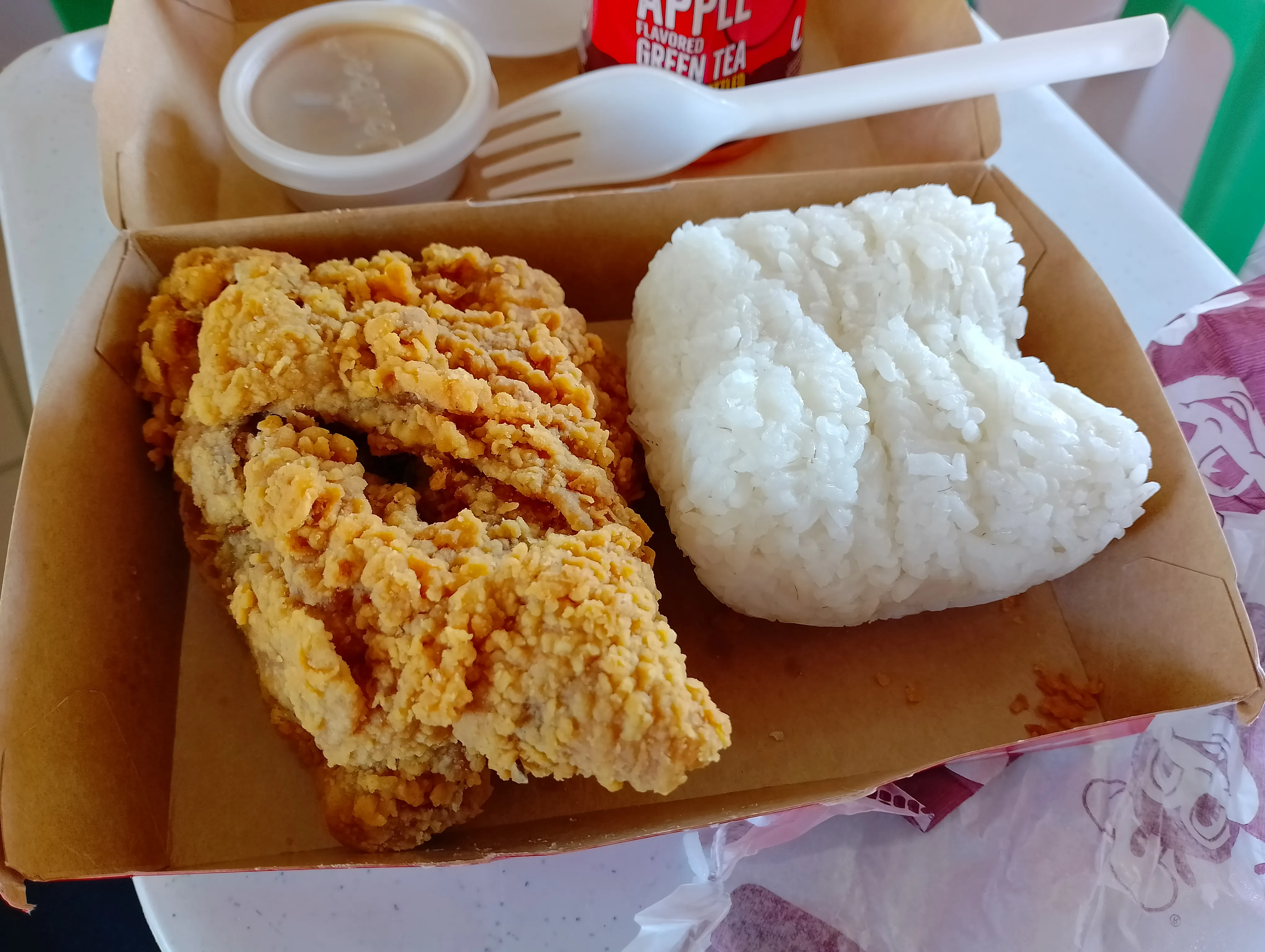 Jollibee Chickenjoy with rice: crispy fried chicken, white rice and a cup of gravy in a takeout box
