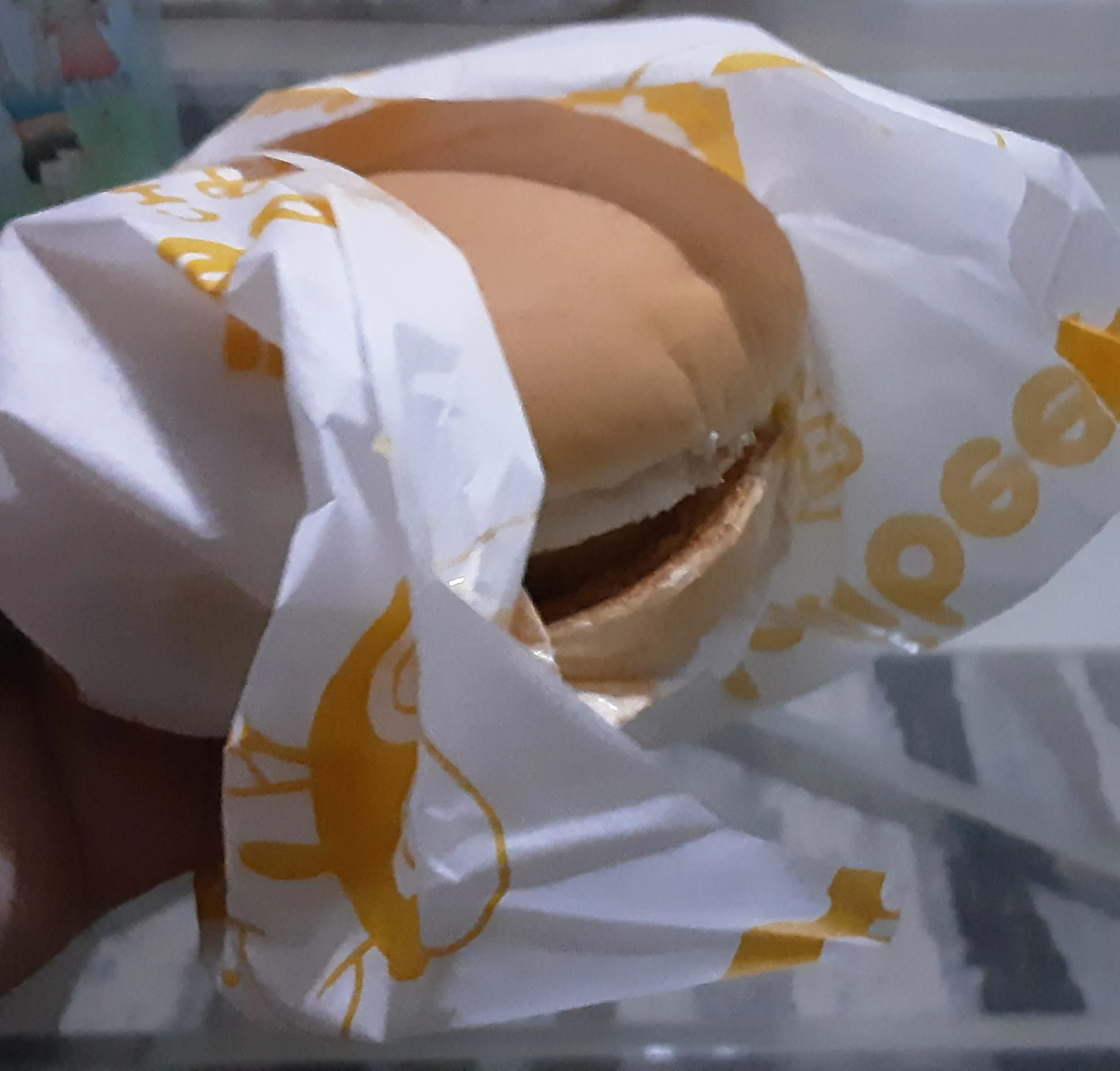 Jollibee Cheesy Yumburger half unwrapped from its yellow-and-white paper