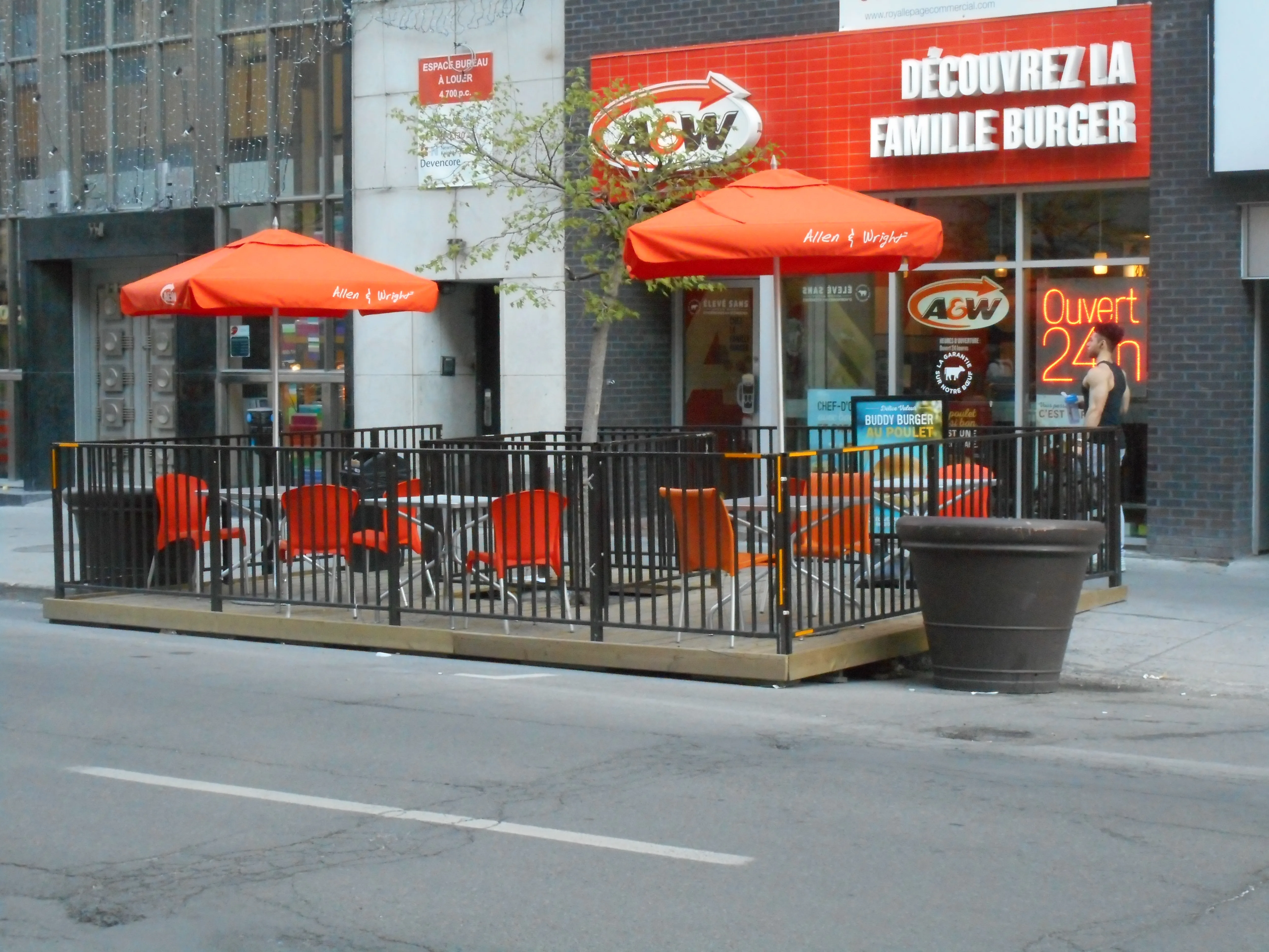 Antiguo A&amp;W del 330 rue Sainte-Catherine Est en Montreal, con terraza de sombrillas naranjas y neón «Ouvert 24h», en 2016