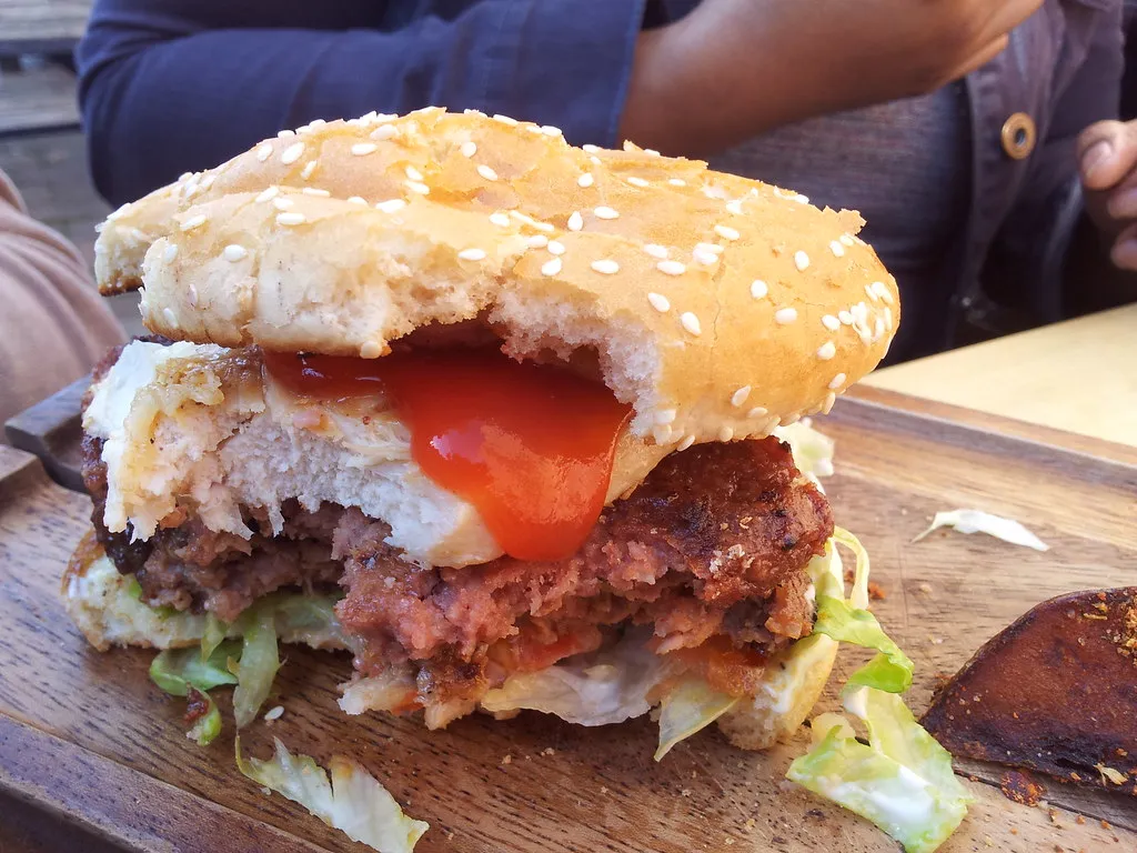 Double-patty burger from Annie’s Burger Shack Nottingham on a wooden board with potato wedges