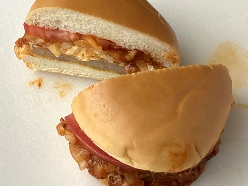 Le MOS Burger signature coupé en deux, avec sa sauce à la viande façon chili et à l’oignon, sa tranche de tomate et son steak : le burger à commander chez MOS Burger à Osaka