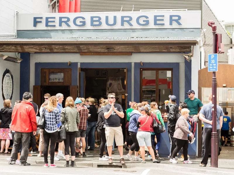 Fergburger Queenstown shopfront at 42 Shotover Street, with customers queuing under the blue Fergburger sign