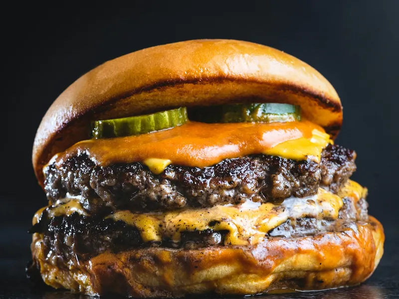 Double smash cheeseburger with crisp edges, melted cheese and pickles, the smash burger style Roses serves in Rosario, Argentina (illustrative photo)