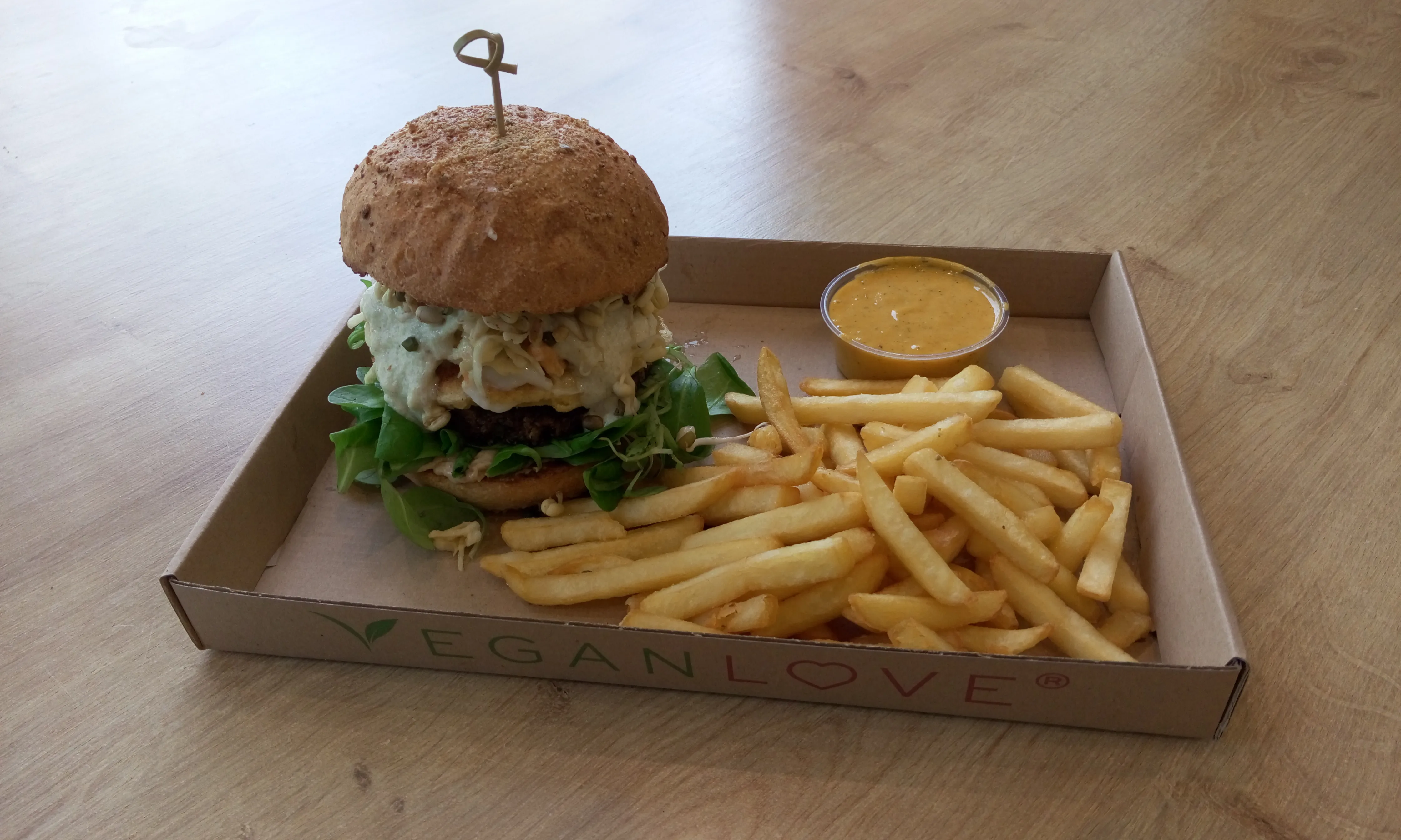 Vegan quinoa burger with greens and creamy sauce in a takeaway tray, illustrative of a healthy quinoa burger