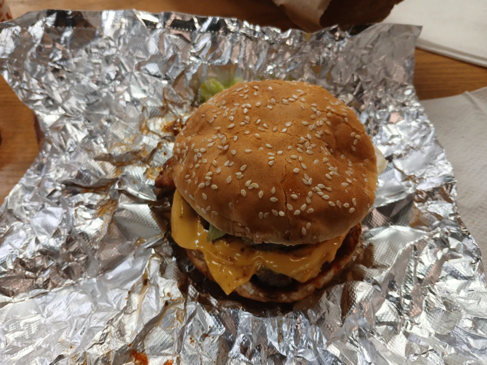Five Guys bacon cheeseburger with melted American cheese on a sesame bun, opened on its foil wrapper, the order we recommend at Five Guys Tampa