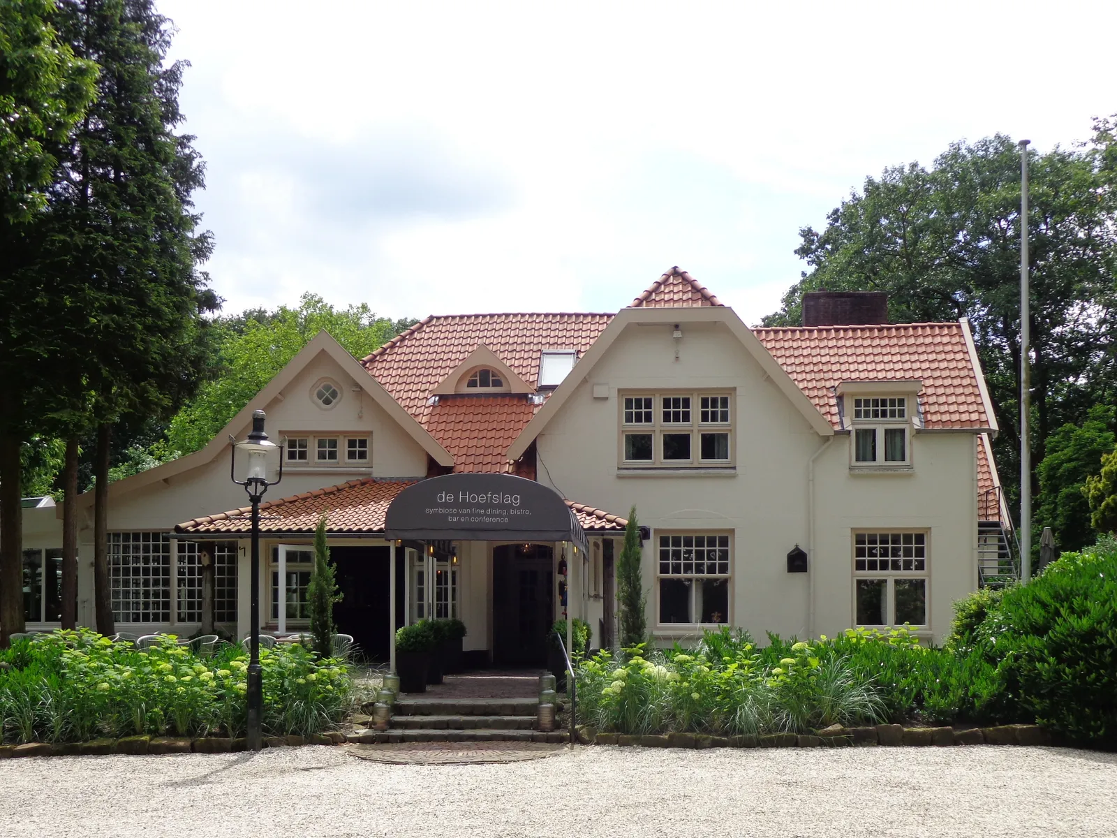 De Hoefslag restaurant in Bosch en Duin near Utrecht, a white villa with a red-tiled roof among the trees at Vossenlaan 28