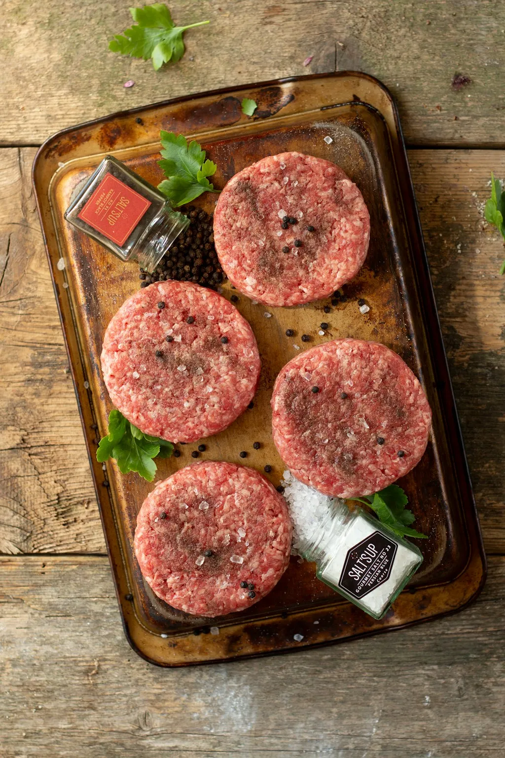 Four raw 80/20 ground beef burger patties shaped loosely before cooking