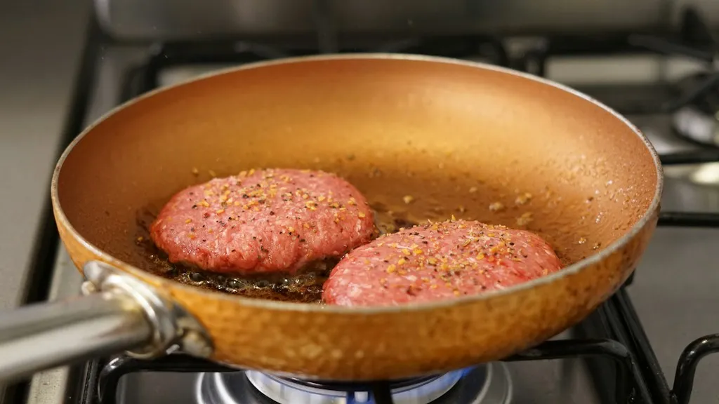 Two thick burger patties searing in a hot skillet