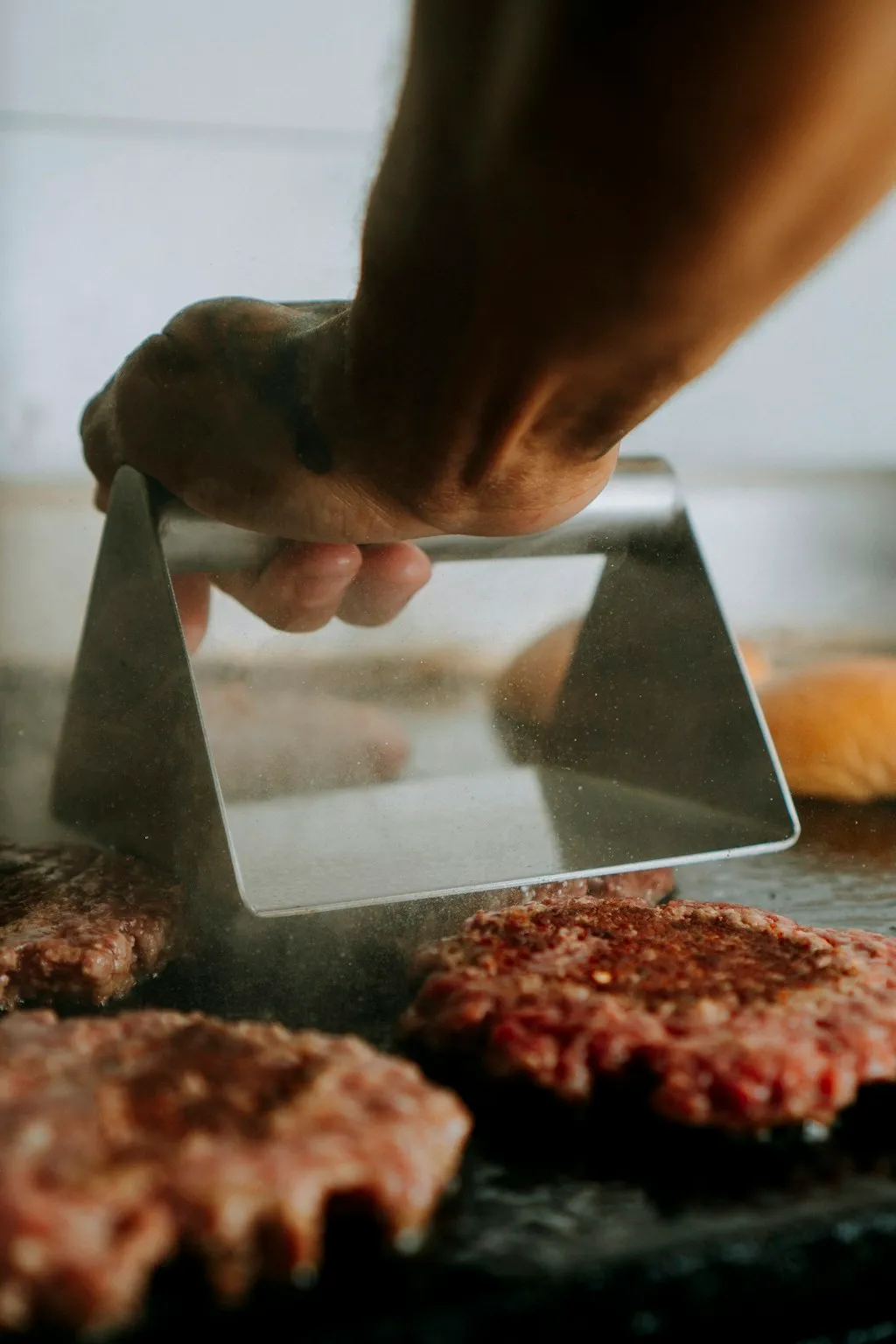Smash burger technique: a ball of ground beef pressed flat on a hot griddle